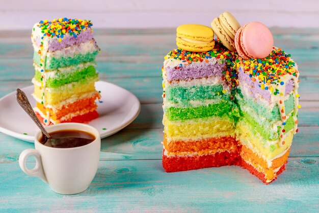 Bolo de arco-íris colorido de aniversário com xícara de café e faca