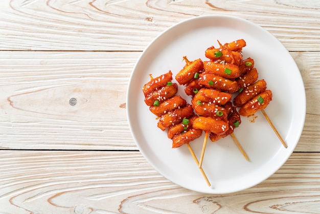 Foto bolo de arroz coreano frito (tteokbokki) espetado com molho picante - comida coreana