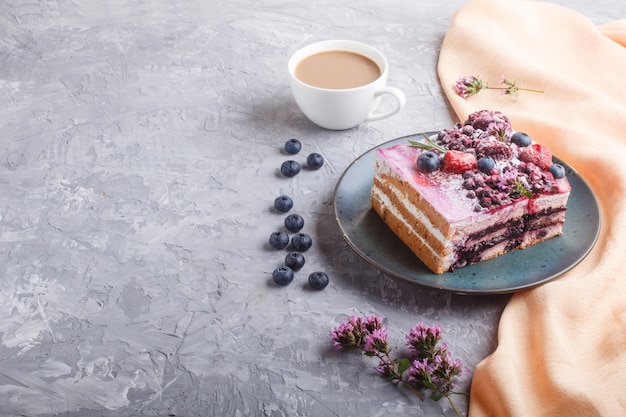 Bolo de Berry com creme de leite e geléia de mirtilo na placa cerâmica azul com uma xícara de café e mirtilos frescos.