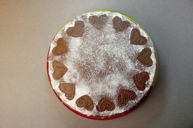 Foto bolo de biscoito de chocolate com creme de cacau com pequenas corações de açúcar em pó. sobremesa. conceito de dia dos namorados. vista superior plana leiga