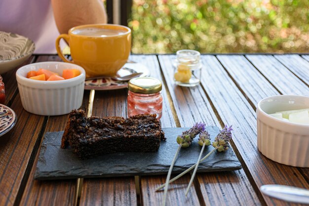 Bolo de biscoito em uma pedra de ardósia, ao lado de flores de lavanda e um pequeno pote de geléia vazio.