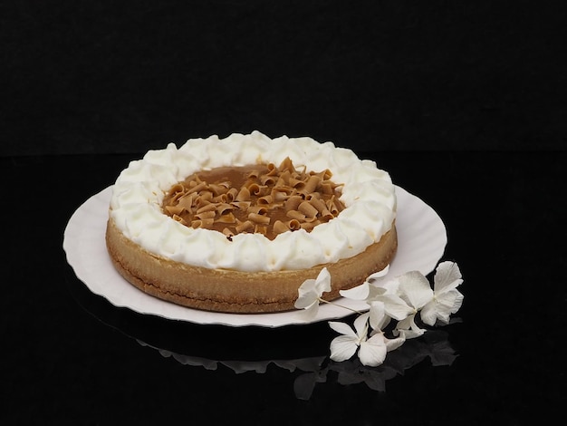 Bolo de biscoito redondo com chantilly de caramelo e chocolate Isolado em fundo preto