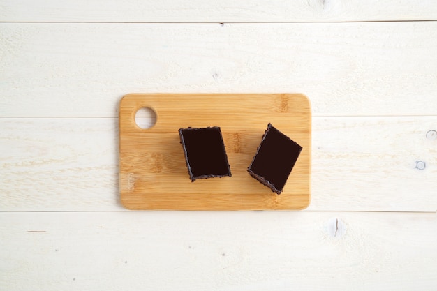 Bolo de brownie em uma bandeja de bambu em um fundo branco de madeira com espaço para texto