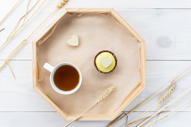 Bolo de caju com coração de chocolate branco e uma xícara de chá em uma bandeja de madeira