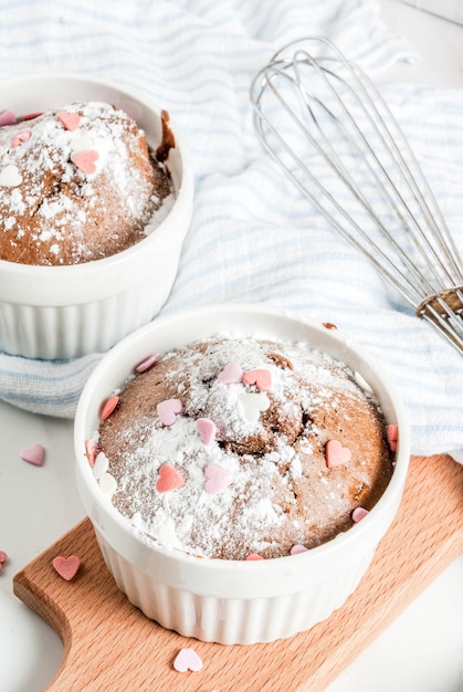 Bolo de caneca de chocolate dia dos namorados ou brownie com açúcar em pó e granulado em forma de coração doce, mesa branca, vista superior