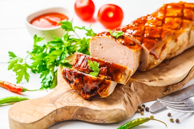 Bolo de carne assado com verduras e molho barbecue em uma placa de madeira