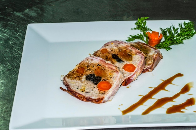 Foto bolo de carne enrolado com molho apresentado em fatias em um prato branco