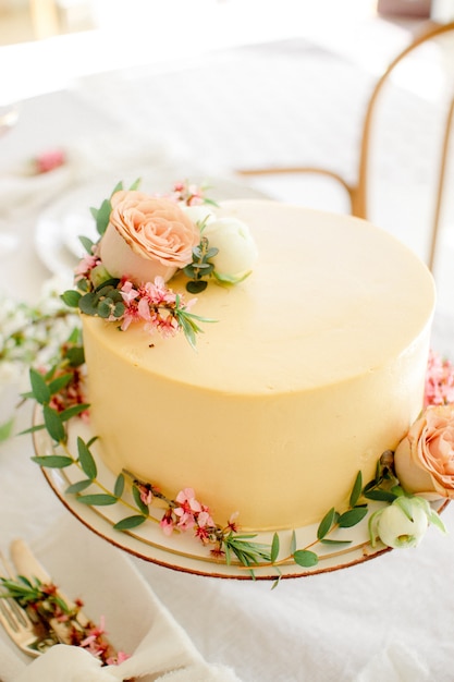 Bolo de casamento amarelo com flores e folhas