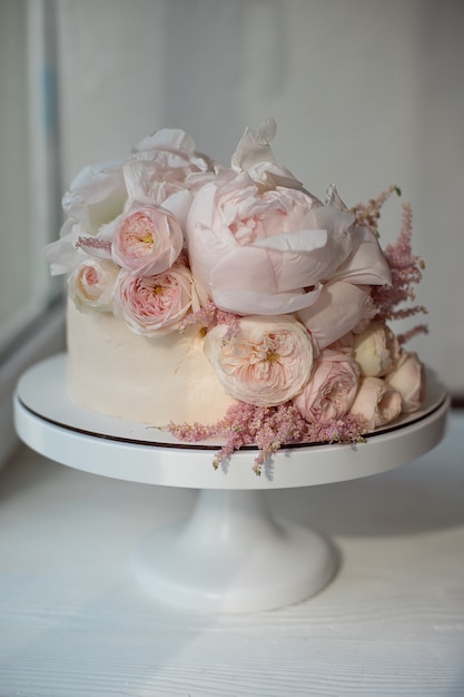 Bolo de casamento branco decorado com rosas frescas, peônias e hortaliças