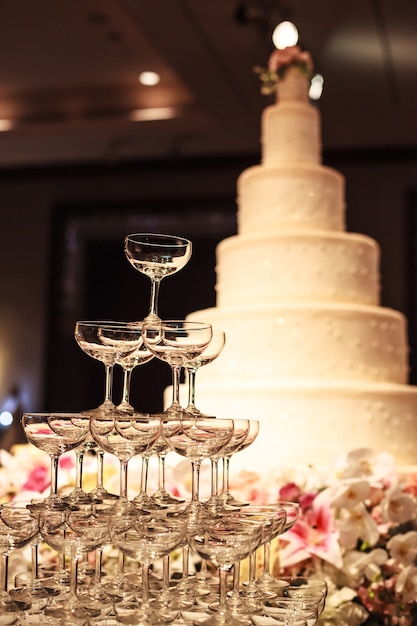 Bolo de casamento com a torre de vidro do champanhe na tabela na fase na cerimônia de casamento.