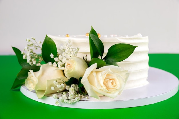 Bolo de casamento com rosas brancas sobre fundo verde. Fechar-se.