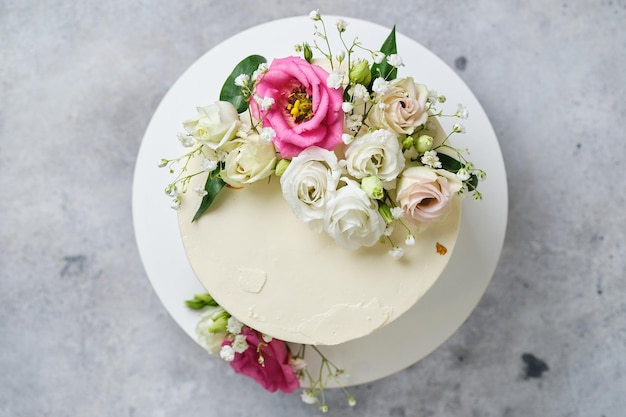 Bolo de casamento lindo e delicioso. O bolo branco é decorado com flores rosas naturais.