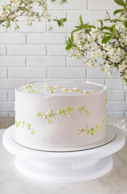 Bolo de casamento rosa em um carrinho entre ramos de flores de cerejeira. decoração delicada no bolo.