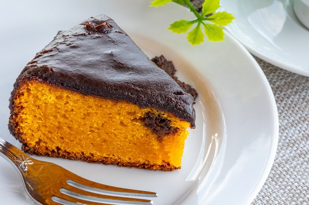 Bolo de cenoura com cobertura de chocolate, acompanhado de uma xícara de café.