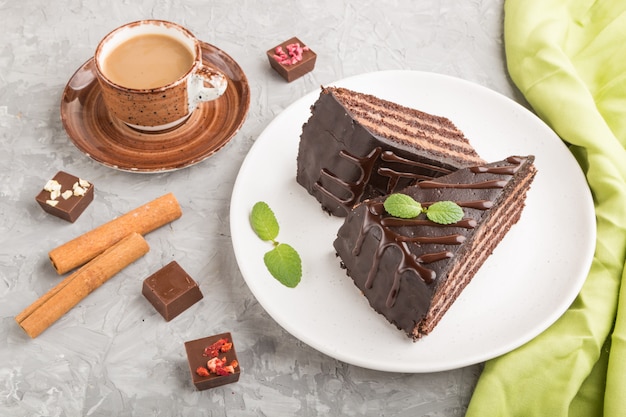 Bolo de chocolate caseiro com creme de leite e uma xícara de café em uma superfície de concreto cinza. vista lateral, close-up.