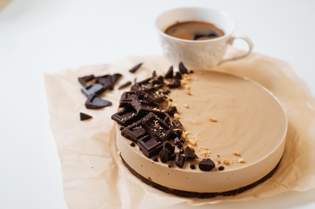 Bolo de chocolate caseiro em papel pergaminho Entrega de alimentos Cozimento caseiro Vista superior Deliciosa torta com chocolate na mesa branca com uma xícara de café