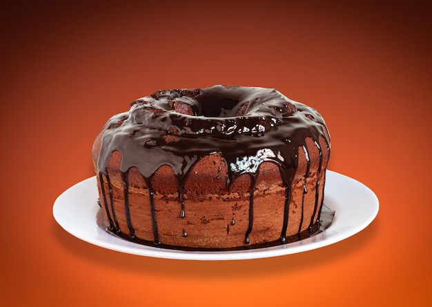 Foto bolo de chocolate com cobertura e fundo laranja