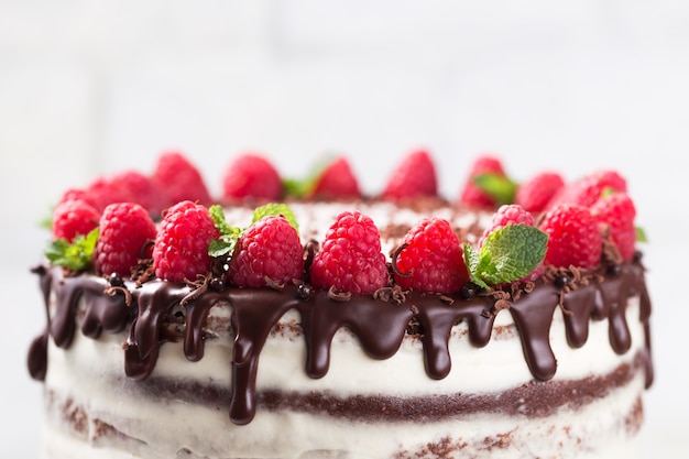 Bolo de chocolate com creme de queijo branco decorado ganache e framboesas