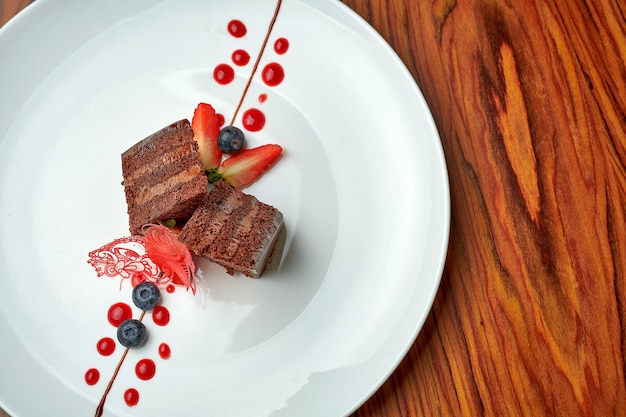 Bolo de chocolate com frutas em um prato branco sobre um fundo de madeira