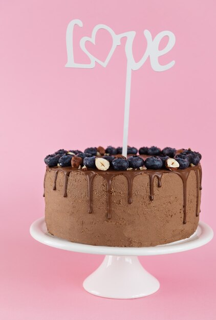 Bolo de chocolate com mirtilos e nozes e a palavra amor em um fundo rosa