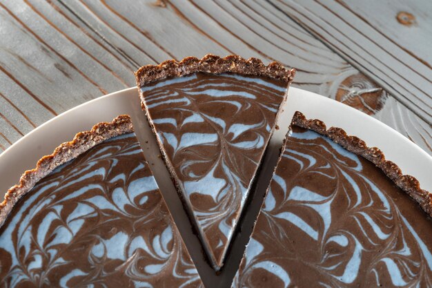 Bolo de chocolate com nozes colocadas em um prato Peça lindamente cortada Fundo escovado de madeira Vegetariano