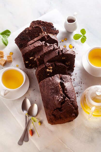 Bolo de chocolate com nozes e ameixas em cima da mesa com chá verde pausa café