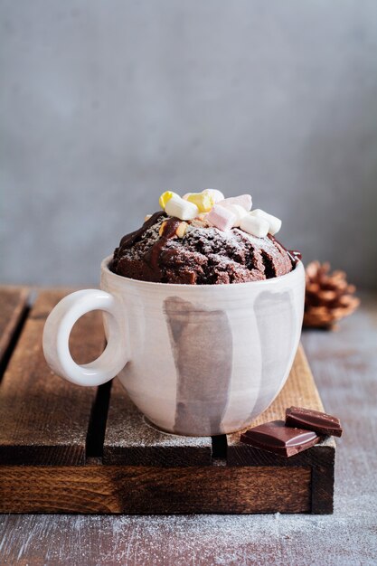 Bolo de chocolate de ano novo cozido em forno de microondas em caneca na textura de superfície cinza vintage