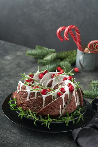 Bolo de chocolate de Natal Bolo tradicional de frutas de Natal com cranberries de esmalte branco e alecrim em fundo escuroDecoração de Natal Cozimento de inverno no Natal ou Ano Novo Copiar espaço