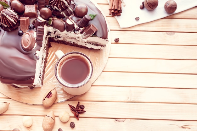 Bolo de chocolate decorado com chocolates com nozes de macadâmia e uma xícara de café