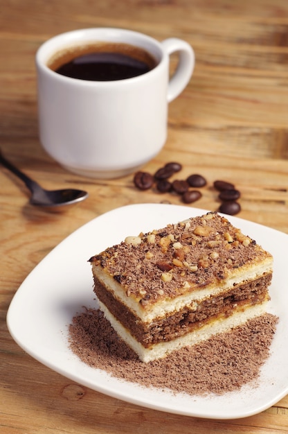 Bolo de chocolate doce e xícara de café na velha mesa de madeira