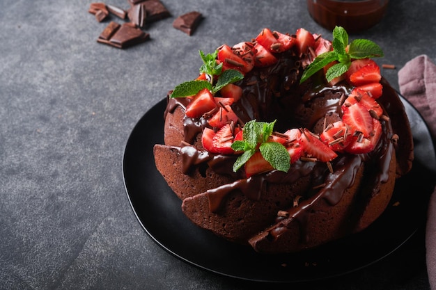 Bolo de chocolate escuro com cobertura de ganache e morango em pedra escura ou fundo de mesa de concreto bolo festivo foco seletivo