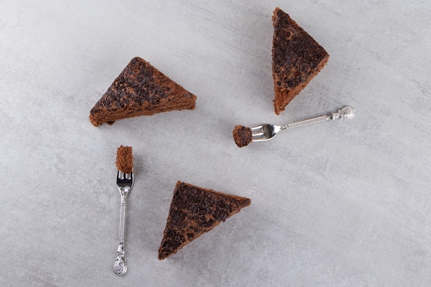 Bolo de chocolate fatiado com garfos colocados sobre uma mesa de pedra.