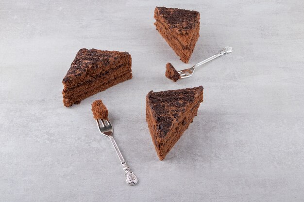 Bolo de chocolate fatiado com garfos colocados sobre uma mesa de pedra.