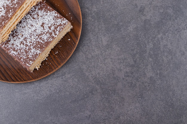 Bolo de chocolate fatiado em prato marrom colocado na mesa de pedra.