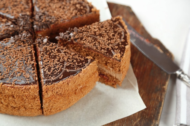 Bolo de chocolate fatiado na mesa de madeira, sobre fundo claro