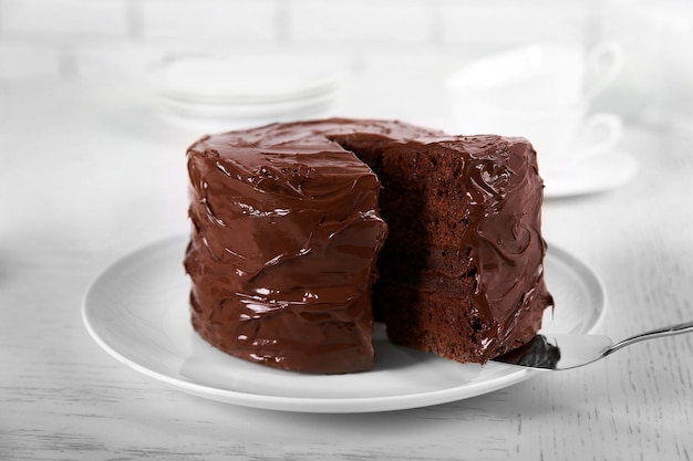 Bolo de chocolate no prato com um pedaço cortado em plano de fundo desfocado