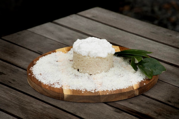 Bolo de coco com glacê e coco ralado na placa de madeira na mesa rústica tropical em outside closeup