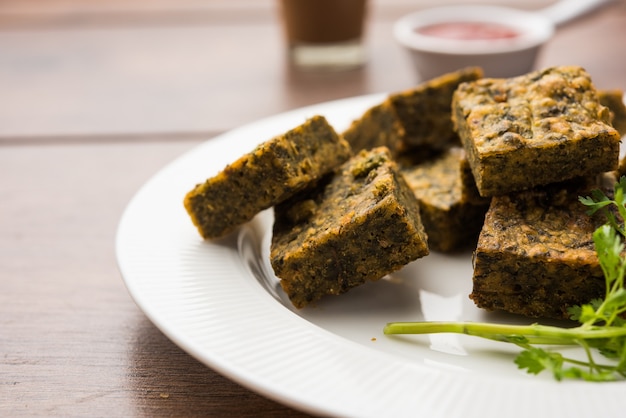 Bolo de coentro ou Kothimbir Vadi é uma culinária popular maharashtriana feita com folhas de coentro. servido com ketchup de tomate. foco seletivo