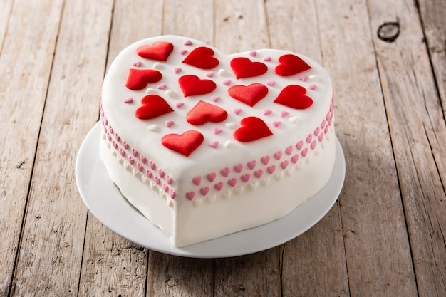 Bolo de coração para o dia dos namorados, dia das mães ou aniversário, decorado com corações de açúcar na mesa de madeira
