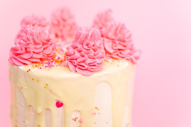 Bolo de creme de manteiga rosa e branco com granulado rosa e gotejamento de ganache de chocolate branco.