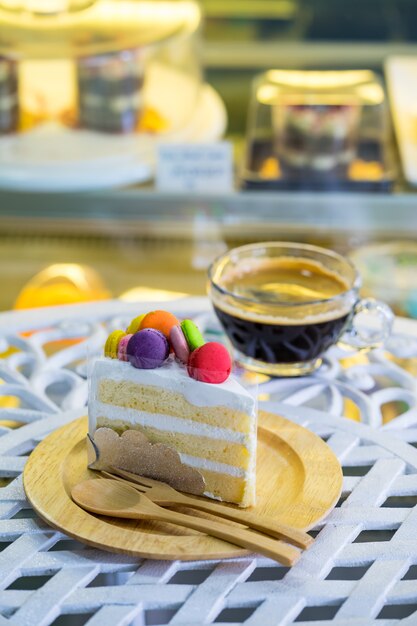 Bolo de creme decorado com macaron no topo, colocado sobre uma placa de madeira