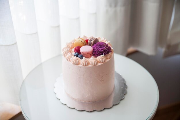 Bolo de creme rosa com macarons mirtilos framboesas flor roxa e pérolas