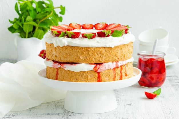 Bolo de esponja Victoria com geléia de morango, chantilly e morangos frescos por cima em um prato branco