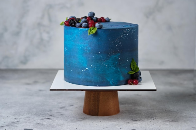 Bolo de estilo espaço delicioso e bonito para um menino ou um homem. Confeitaria para o feriado. A sobremesa é decorada com mirtilos frescos, amoras, groselhas e chocolate.