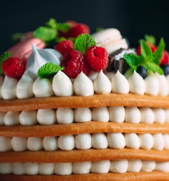 Bolo de frutas. Bolo decorado com frutas em um carrinho de madeira em um fundo preto.