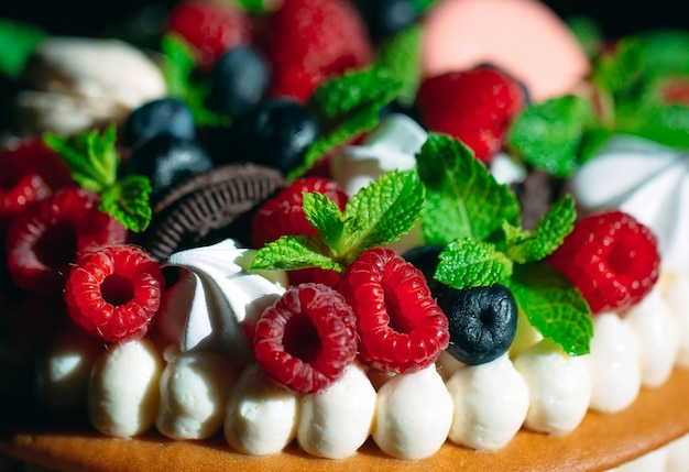 Bolo de frutas. Bolo decorado com frutas no carrinho de madeira em preto