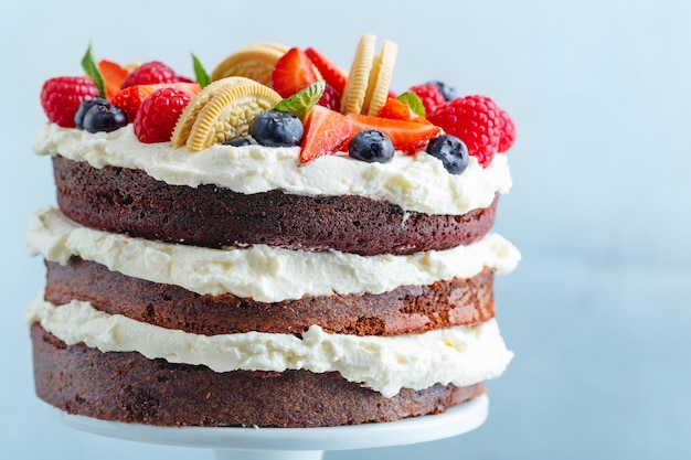 Bolo de frutas com frutas frescas e creme em stander no fundo brilhante.