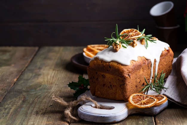 Bolo de frutas polvilhado com glacê, nozes e laranja seca em madeira velha. bolo caseiro de férias de natal e inverno