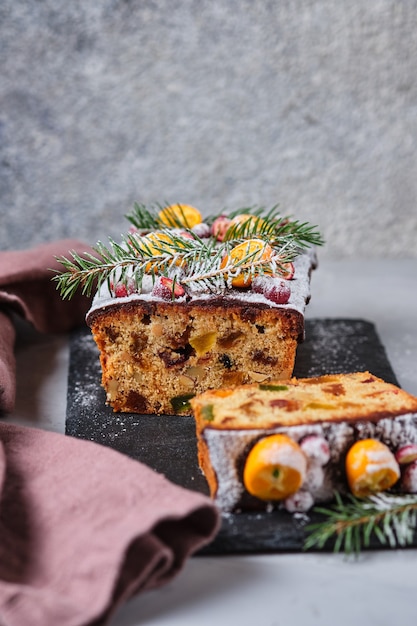 Bolo de gengibre de ano novo com kumquat, frutas secas e frutas. Uma sobremesa festiva decorada com ramos de abeto e bagas e frutos frescos.