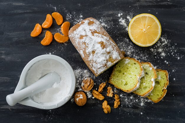 Bolo de hortelã polvilhado com açúcar em pó na superfície escura com tangerinas de laranjas frescas